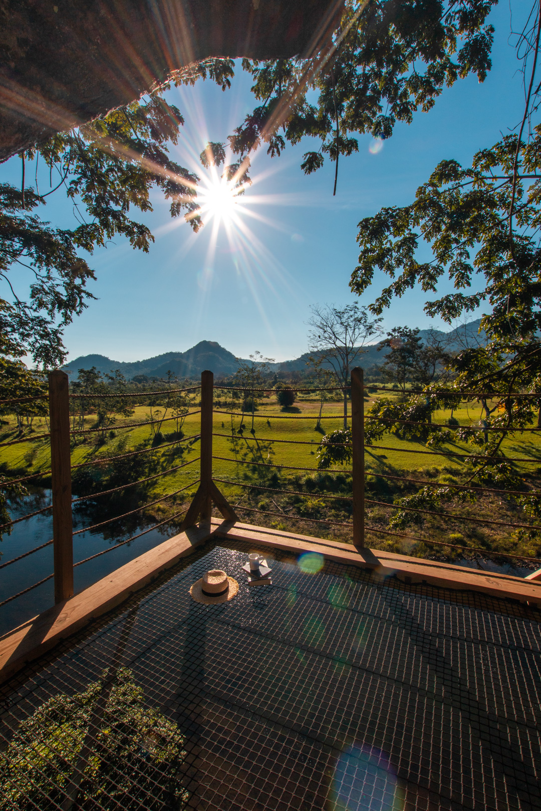 The view from the treehouse showing the sun and mountains in the distance at The Rainforest Lodge at Sleeping Giant