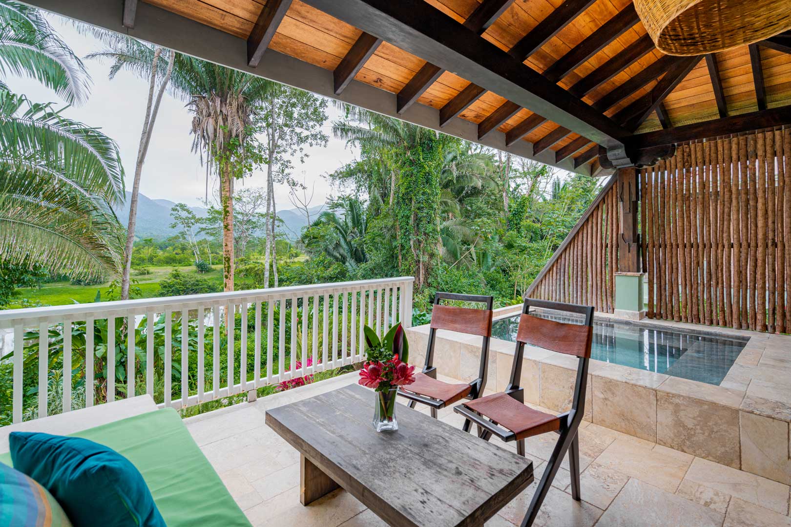 The private balcony with a small table, two folding chairs and a couch along with a plunge pool outside of the Riverview Suite with Plunge Pool at The Rainforest Lodge at Sleeping Giant