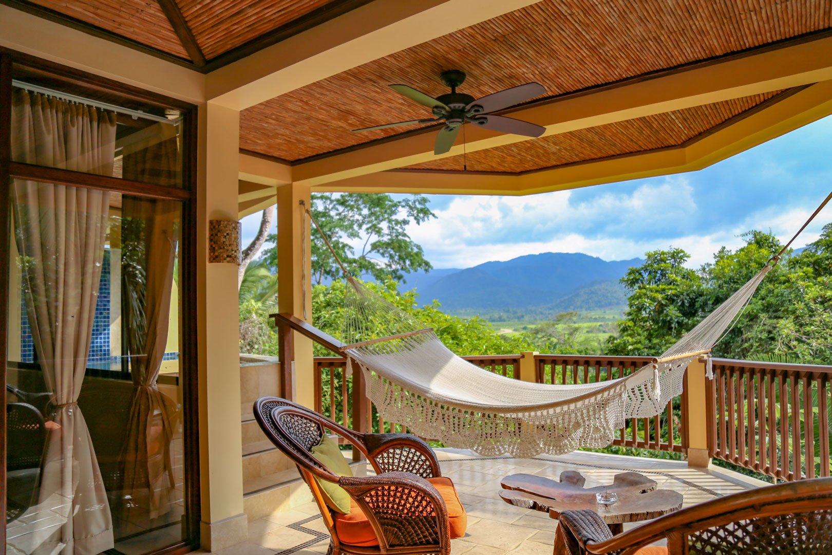 The private balcony with a small table and seating along with a hammock outside of the Mountain View Suites at The Rainforest Lodge at Sleeping Giant