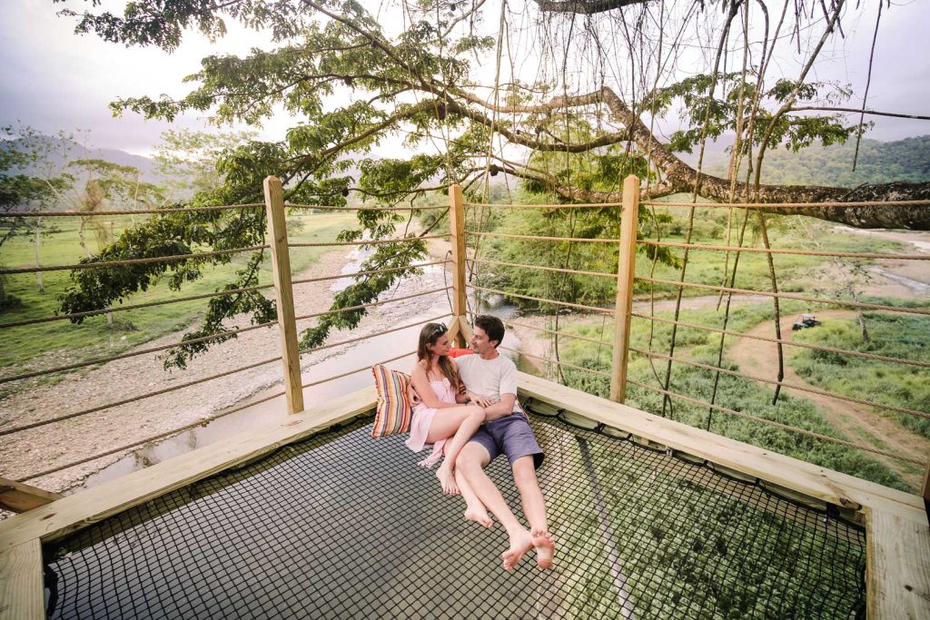 A couple sitting in the net hammock at the top of the treehouse at The Rainforest Lodge at Sleeping Giant