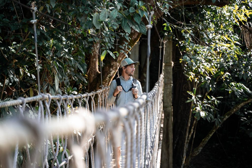 A guest standing on a rope bridge at The Rainforest Lodge at Sleeping Giant