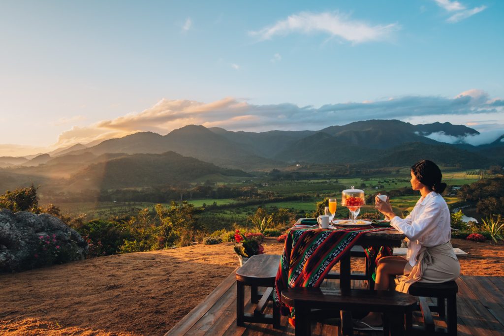 A guest sitting at a picnic table at the cliff watching the mountains at The Rainforest Lodge at Sleeping Giant