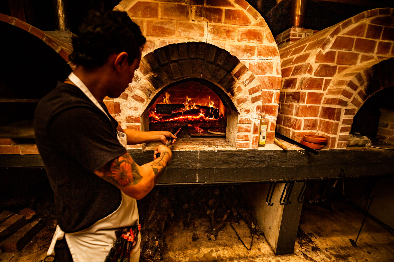 A pizza maker adding a pizza to the pizza oven at Don Tonito's Pizzeria.